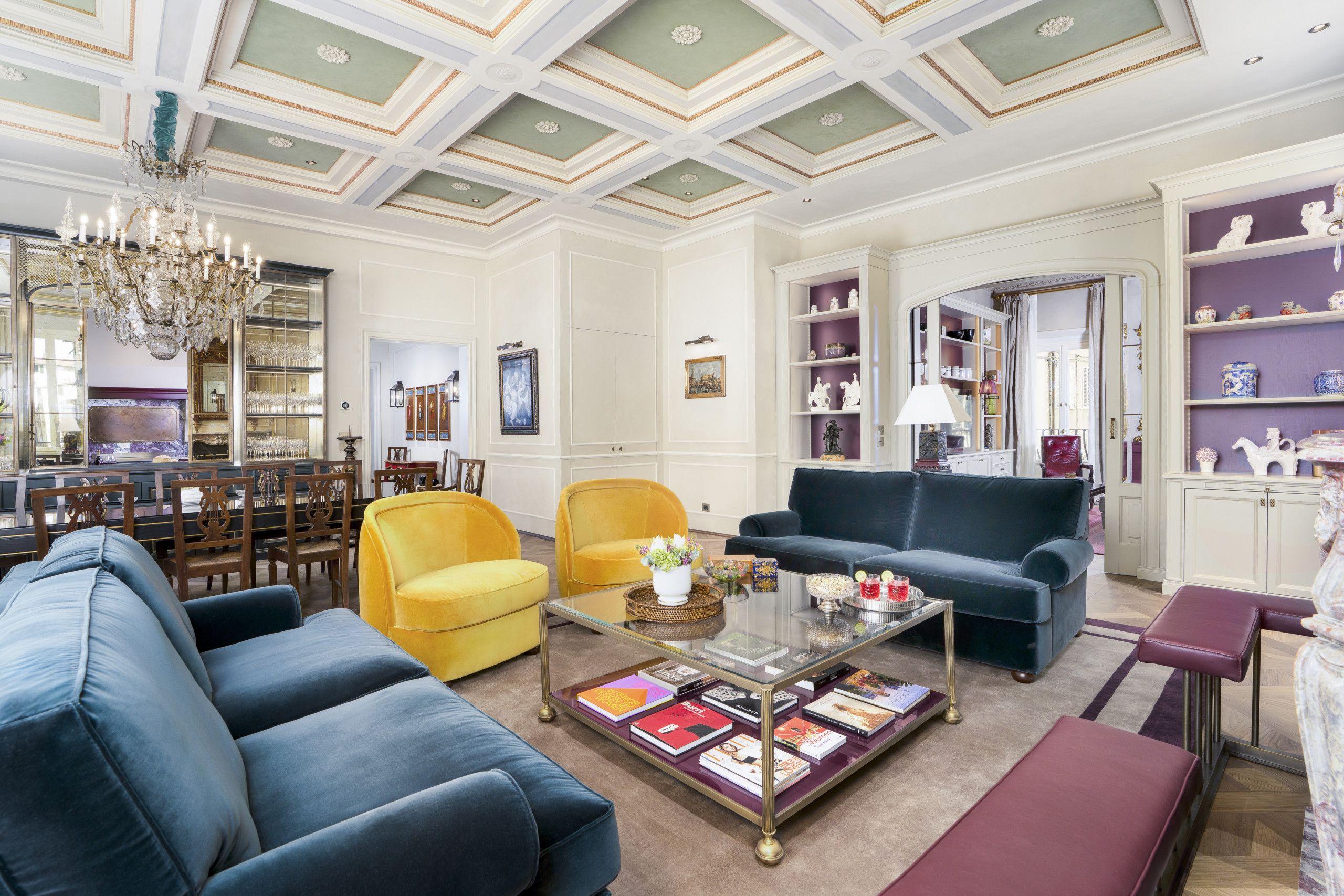 A spacious living room with a high ceiling, a chandelier, and a variety of seating options including sofas and chairs.