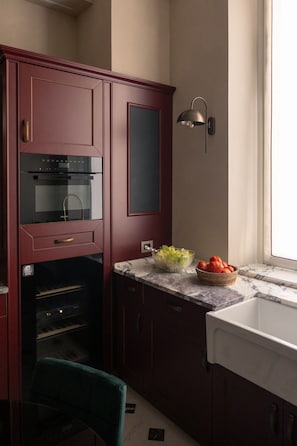 A kitchen with a built-in oven, a marble countertop, a bowl of fruit, and a wall-mounted light fixture. - Dimora Dell’Arcangelo Piano Nobile (Lucca)
