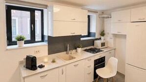 Una cucina moderna con mobili bianchi, un piano cottura a gas, un forno a microonde e un lavello.