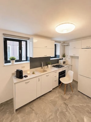 A modern kitchen with white cabinets, a gas stove, a microwave, and a sink. - Modern & Elegant Apartment | King Bed (Bucharest)