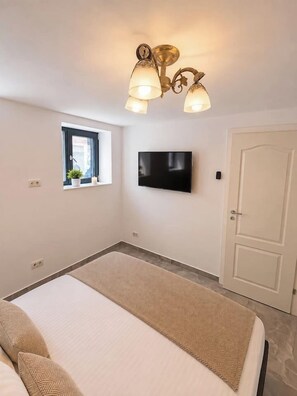 A bedroom with a bed, a television, a window, and a door. - Modern & Elegant Apartment | King Bed (Bucharest)