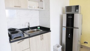 Una cocina compacta con estufa, lavamanos y refrigerador de dos puertas.