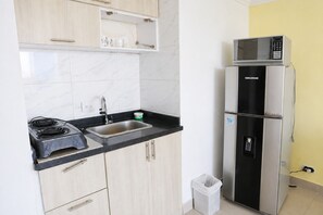 A compact kitchen with a stove, sink, and a double-door refrigerator. - Encantador Apartamento Frente a la Playa (Cartagena de Indias)