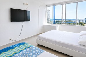 Ein Schlafzimmer mit einem Bett, einem an der Wand montierten Fernseher und einem Fenster mit Blick auf die Stadt.