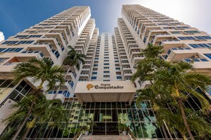 Een hoog hotelgebouw met meerdere verdiepingen, een opvallende ingang en omlijstende palmbomen.