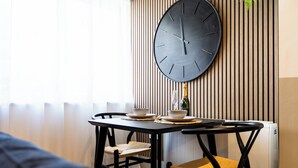 A dining area with a table, chairs, a large wall clock, and a bottle of champagne. - Pelican House No.6 | Luxury Apartment | Walk to the Beach | Bournemouth Centre (Bournemouth, Christchurch and Poole)