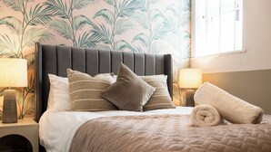 A neatly made bed with a dark headboard, multiple pillows, and a rolled towel. - Pelican House No.6 | Luxury Apartment | Walk to the Beach | Bournemouth Centre (Bournemouth, Christchurch and Poole)
