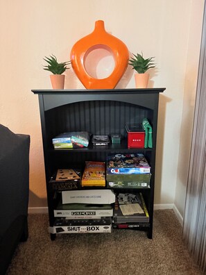 A bookshelf with various board games and a toilet paper holder.