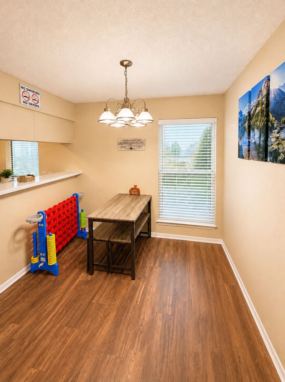 A dining area with a wooden table and bench, a red radiator, a ceiling light fixture, and a window with blinds.