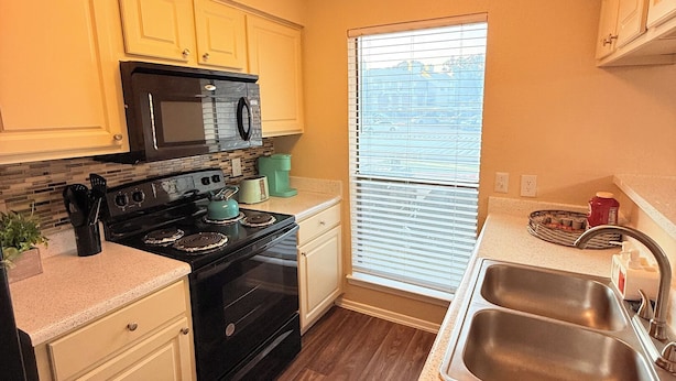 A compact kitchen with a stove, microwave, and sink.