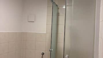Ein Badezimmer mit Toilette, einer Duschkabine aus Glas und einer Deckenleuchte.