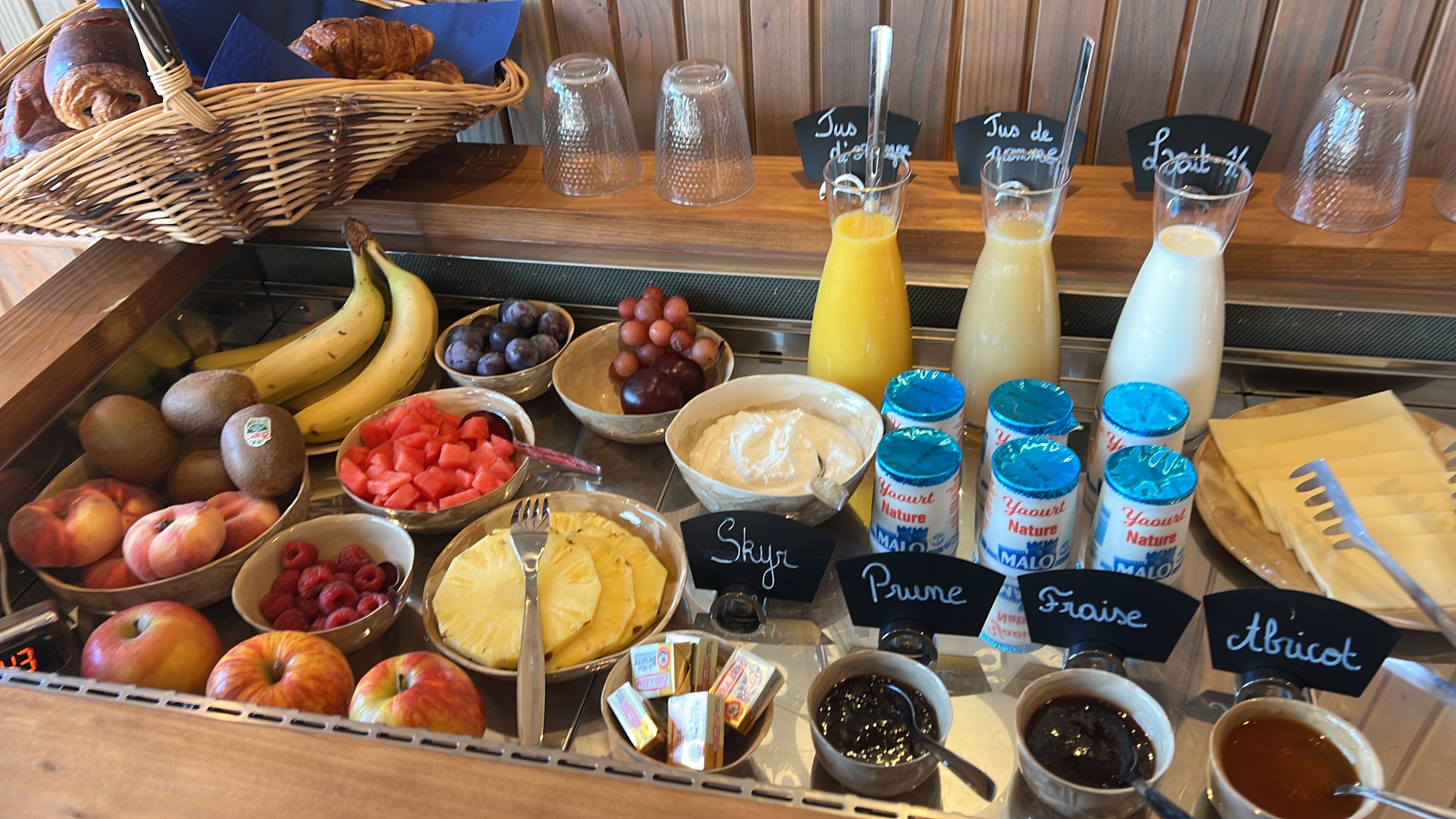 A breakfast buffet with various fruits, yogurts, and beverages.