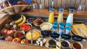 A breakfast buffet with various fruits, yogurts, and beverages. - Le Groom Hôtel (Laprade)