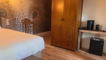 Une chambre à coucher comprenant un lit, une armoire en bois, un bureau avec un ordinateur et un mur décoré d’un motif.