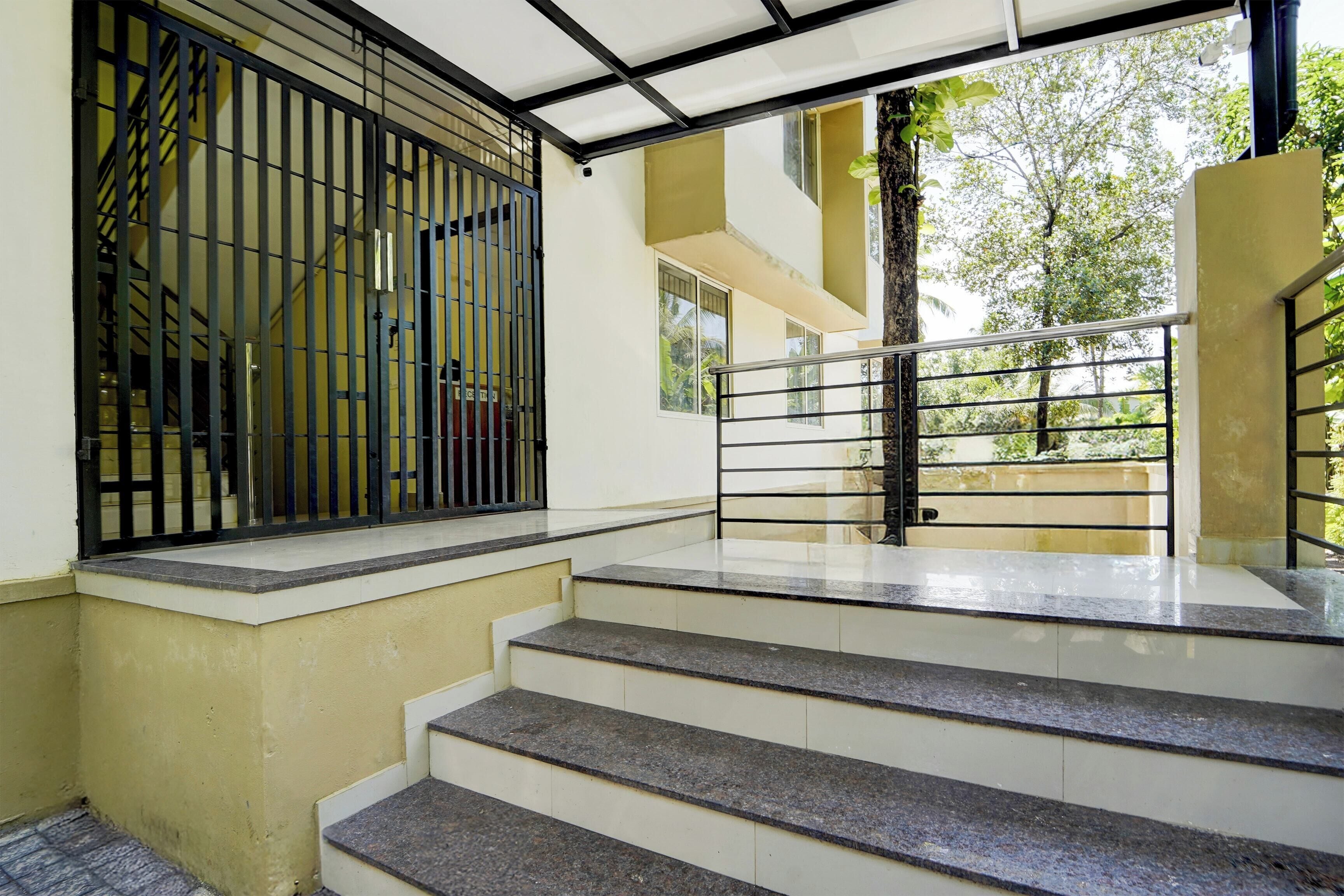 A staircase with a metal railing leading to a covered area with a view of greenery outside.