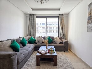 Un salon comprenant un ensemble de canapés, une table basse et une vue dégagée sur l’extérieur grâce à une grande fenêtre.