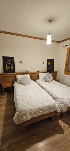 Et værelse med to senge, trægavle, et lille bord og en hængende lampe.