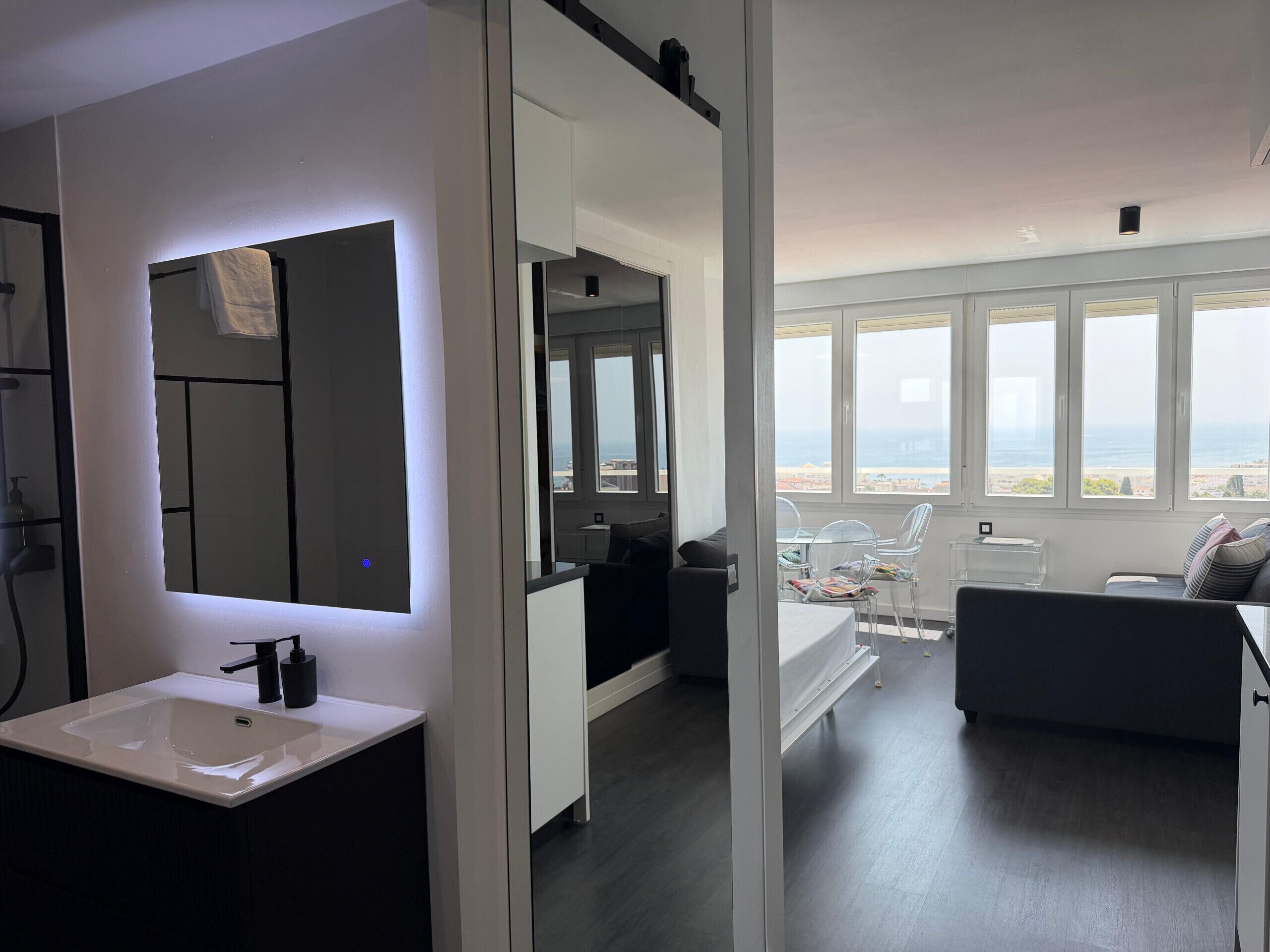 A modern bathroom with a large mirror and a white sink.