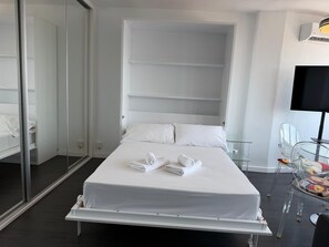 Une chambre d’hôtel moderne équipée d’un lit, d’une télévision et d’une table en verre.