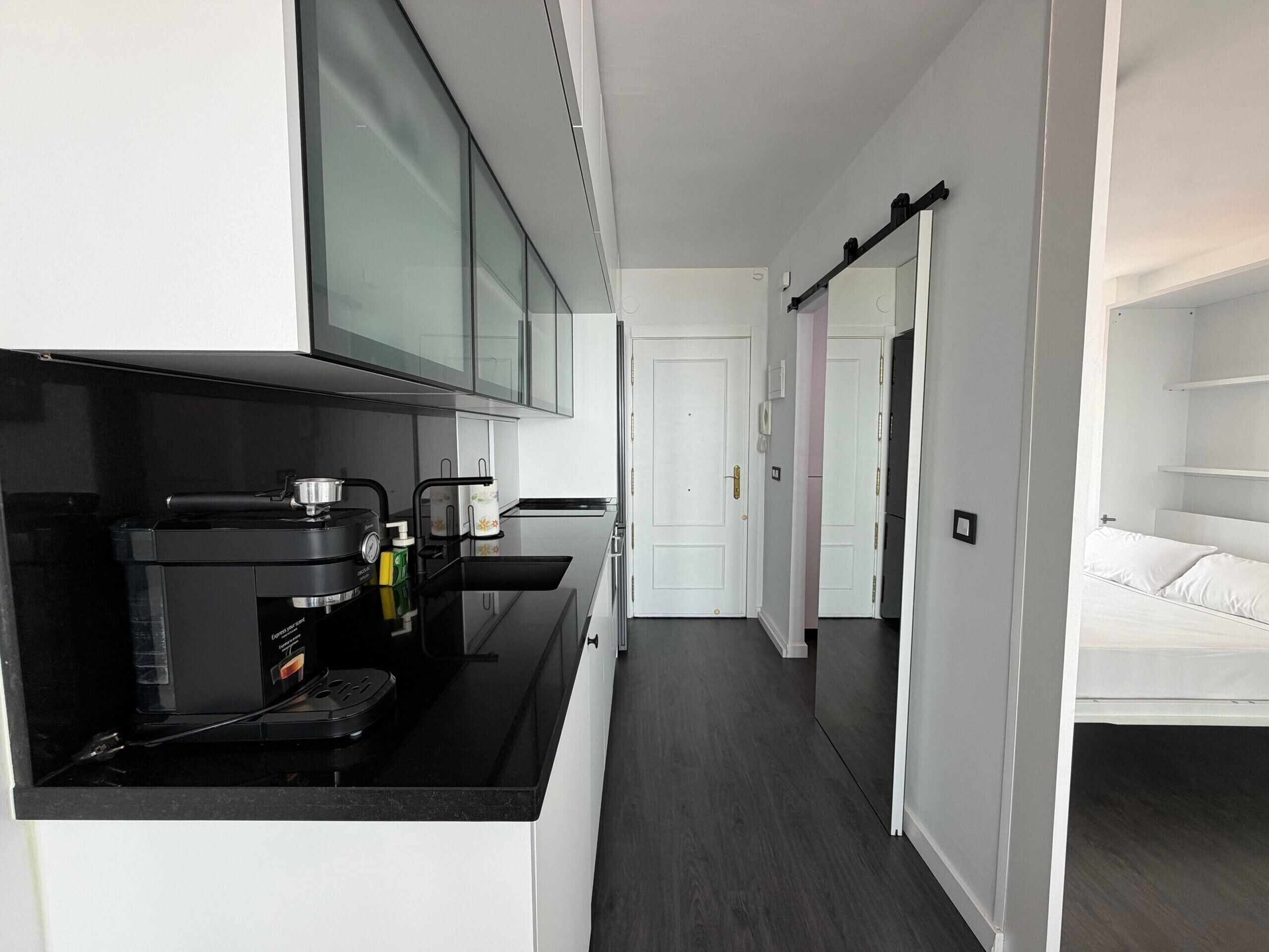 A compact kitchen with a coffee machine, a microwave, and a small sink.