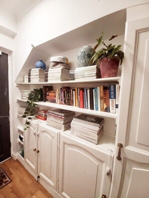 A bookshelf with books and decorative items, a potted plant, and a door with a doorknob. - Kensington Studio Gem - Rare find by Holland Park (Greater London)