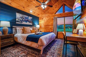 Ein Schlafzimmer mit einem Bett, Nachttischen, einem Schreibtisch und einem großen Fenster.