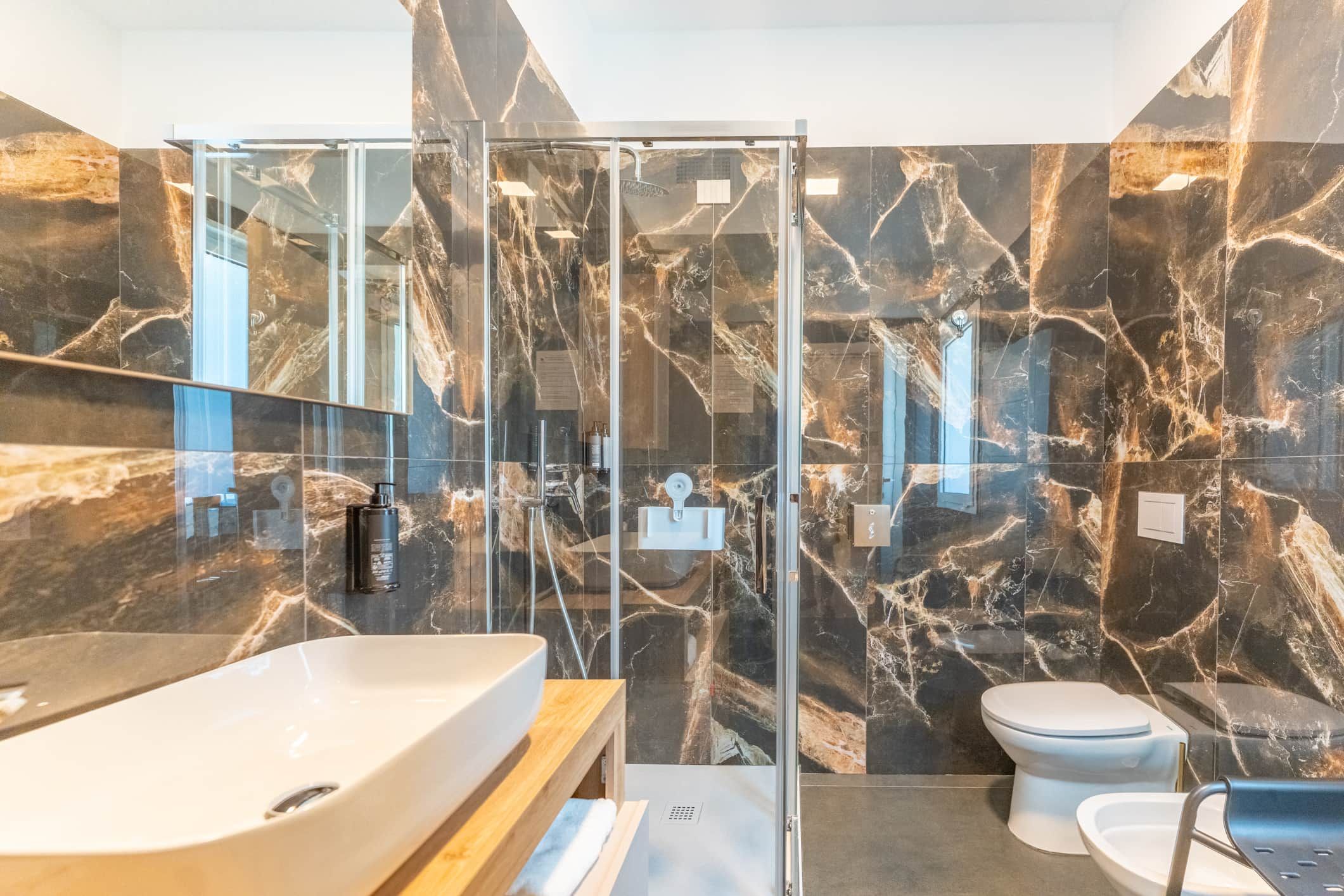 Un baño moderno con ducha vidriada, lavamanos grande y retrete.