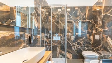 Un baño moderno con ducha vidriada, lavamanos grande y retrete.