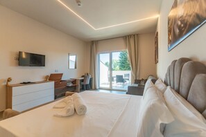 A hotel room with a bed, a desk, a chair, a television, and a view of the outdoors. - Suite with a terrace overlooking the lake | Lagorá – C7 (San Giuliano Milanese)