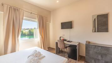 Una habitación de hotel con cama, escritorio, silla, televisor y vista al lago.