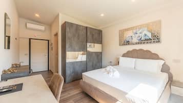 Una habitación de hotel con cama, escritorio, silla, armario y un cuadro en la pared.