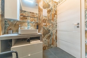 Ein Badezimmer mit Marmorwaschbecken, einem Spiegel und einer Duschkabine.