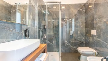 Un bagno moderno con cabina doccia in vetro, lavandino bianco e water.