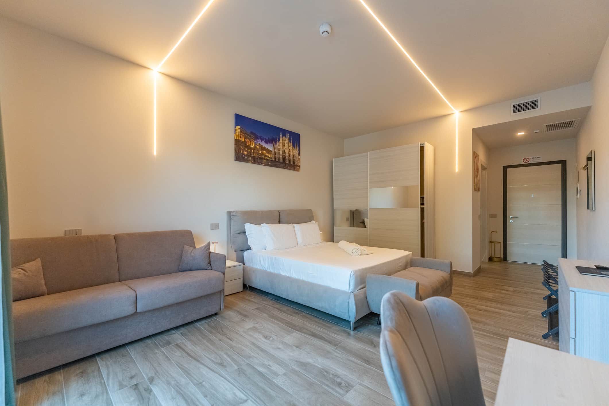 Una habitación de hotel moderna con sofá, cama, escritorio y silla.