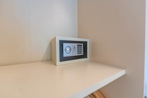 A secure electronic safe with a keypad and a circular lock mechanism on a white shelf.
