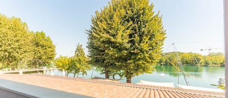 A balcony with a view of a lake and trees.