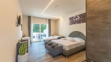 A modern hotel room with a bed, a sofa, a coffee table, and a potted plant.
