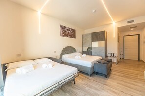 Ett hotellrum med två sängar, en soffa, en stor spegel och en dörr med en skylt.