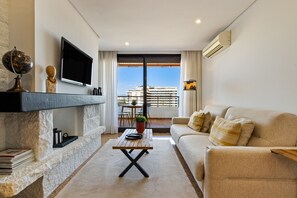 A modern living room with a sofa, a flat-screen TV, a globe, and a balcony with a view of a cruise ship. - Casa Lamela 63 - La Nogalera, Terrace & Pool (Torremolinos)