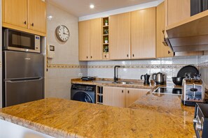 A kitchen with wooden cabinets, a stainless steel refrigerator, a built-in oven, a washing machine, a sink, and a stove. - Casa Lamela 63 - La Nogalera, Terrace & Pool (Torremolinos)