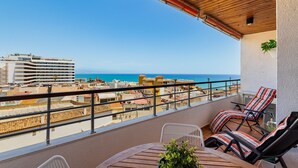 Un balcon avec vue sur la mer, une table avec des chaises et une plante en pot.