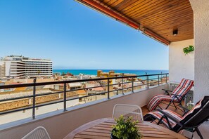 Ein Balkon mit Meerblick, einem Tisch mit Stühlen und einem Blumentopf.