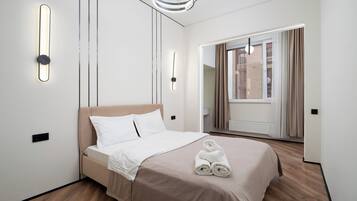 A modern hotel room with a bed, bedside lamps, a mirror, and a view of the outside.