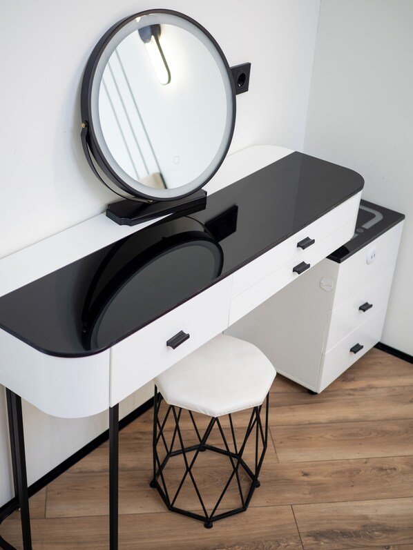 A modern vanity with a round mirror, black countertop, and white drawers. - Cozy apartments in the business district (Almaty)