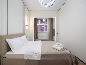 A modern hotel room with a bed, a view through a window, and a neatly made bed with towels. - Cozy apartments in the business district (Almaty)