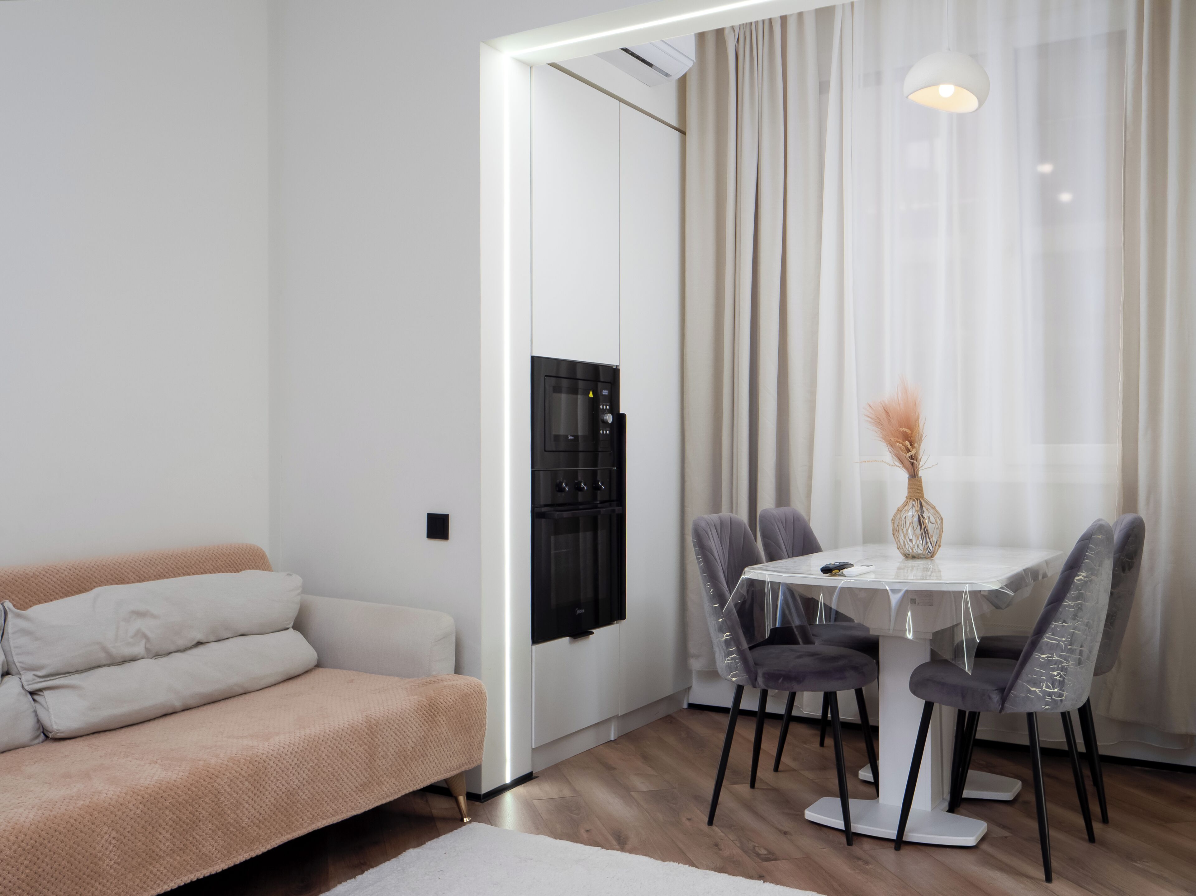 Un espace de vie moderne comprenant un canapé, une table à manger, des chaises et un appareil de climatisation.