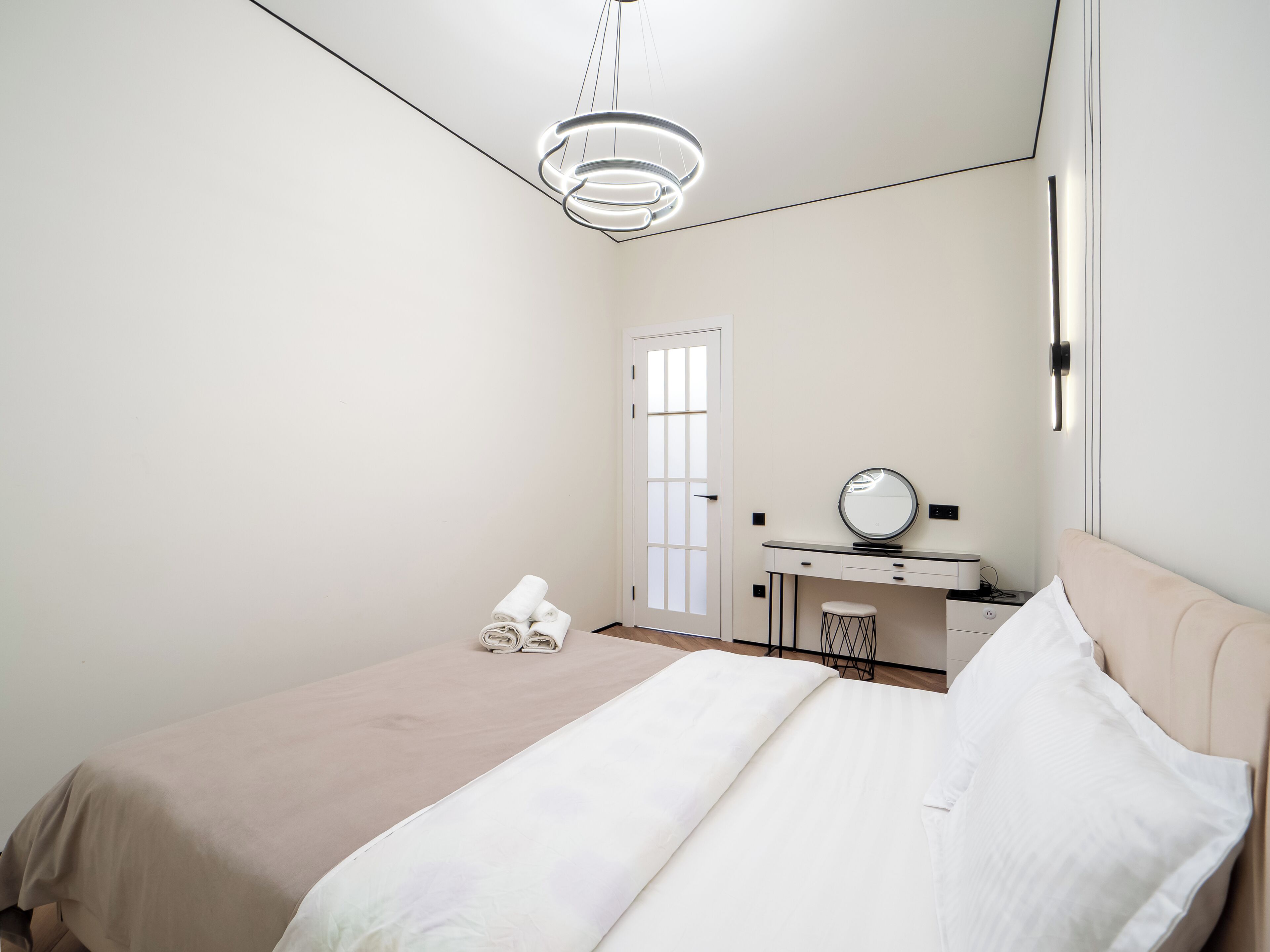 Ein Schlafzimmer mit einem Bett, einem Schreibtisch mit Spiegel und einer Tür.