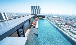 A rooftop pool with lounge chairs and a city view. - Sea View 2 Bed Room Good Location (Pattaya)