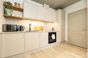 Eine moderne Küche mit weißen Schränken, einem Backofen und einer Mikrowelle.