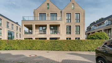 Un immeuble résidentiel moderne à deux étages, doté d’une façade en briques, de grandes fenêtres et d’un balcon.